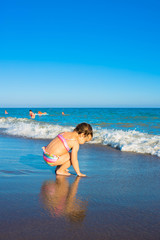 Little child girl playing on the sea beach.
