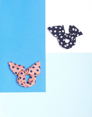 Colorful dotted hair bands or bracelets with bows on blue and white background. Flat lay. Top view.