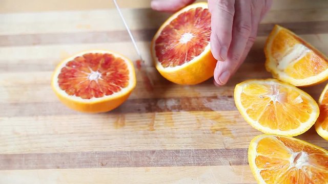 A man prepares blood oranges on a cutting board