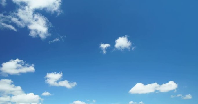 Time lapse video of white cumulus clouds running across blue sky