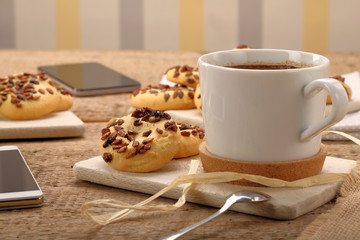 Cup of coffee cup with crunchy cookie on the table and smart phone