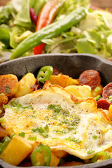 fried egg and baked potatoes with sausage chorizo on frying pan