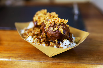 Meatballs with rice and crispy onion in a food truck.