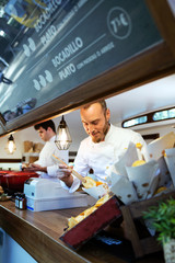 Fototapeta na wymiar Young chef serving barbecue potatoes in a food truck.
