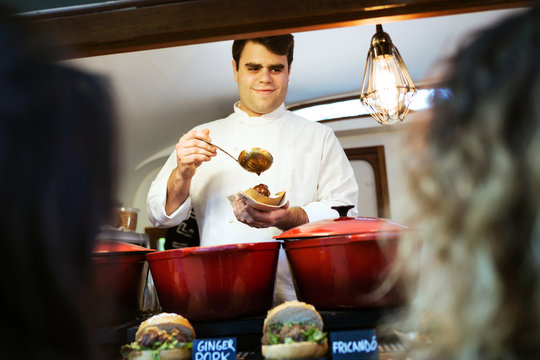 Young chef serving meatballs to two pretty girls in a food truck.