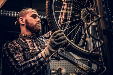 Mechanic doing bicycle wheel service manual in a workshop.