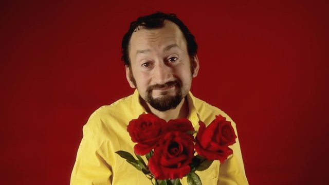 A funny ugly man offers a handful of red roses to the viewer. Valentine's day, dating, anniversary, unexpected, unwanted.
