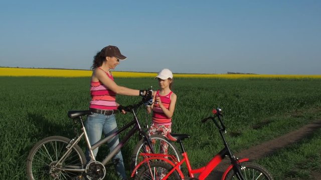 Cyclists drink water. Mom gives her daughter water.