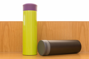 green and black vacuum tumblers on a wood table