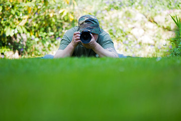 ein Fotograf liegt auf einer Wiese und macht Naturfotos