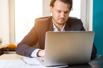 Businessman working laptop in modern loft office at sunset