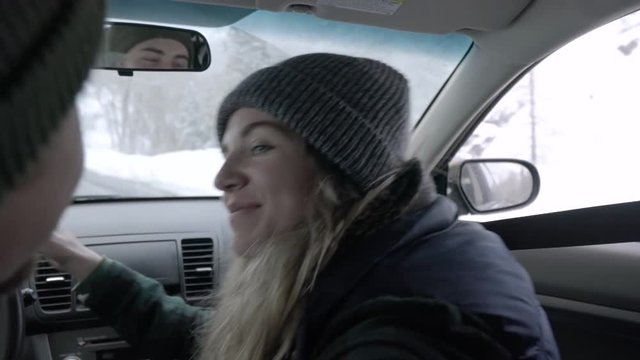 Man Gestures For His Girlfriend To Kiss Him, She Kisses Him On The Cheek And Then Lips, While They Drive Slowly Up Mountain Road