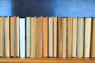 Books on the wooden shelf turned by a cover back