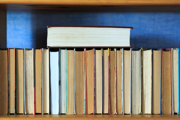 Books on the wooden shelf turned by a cover back