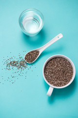 Glass of water with cup of healthy chia seeds and spoon. Text space.