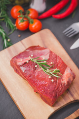 Raw beef on a cutting board  with spices and ingredients for cooking.