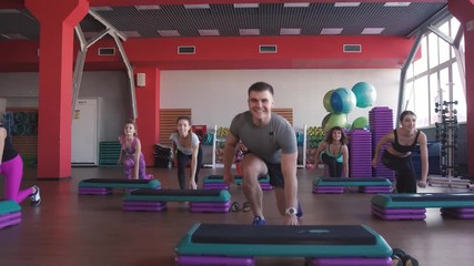 Step aerobics exercise class - group of people exercising on steppers with the trainer.