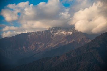 Morning view of snow-capped mountains with clouds drifting over the peaks in a scenic alpine landscape