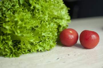 Bunch of raw organic green frisee salad and two tomatoes