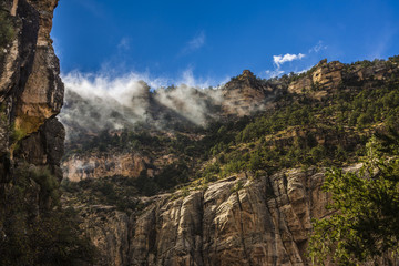clouds hanging low over the canyon rim on a sunny day