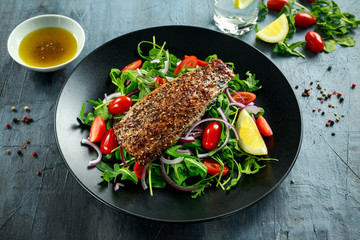 Smoked Mackerel Salad with tomato, chopped red onion, Ruccola on black plate.