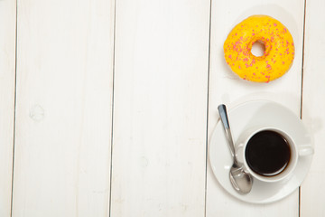 Cup with coffee and donuts on a white wooden table