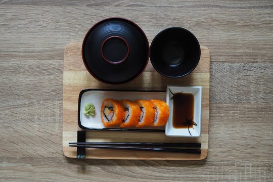California maki roll in square plate Japanese style served with shoyu sauce and wasabi on table wood