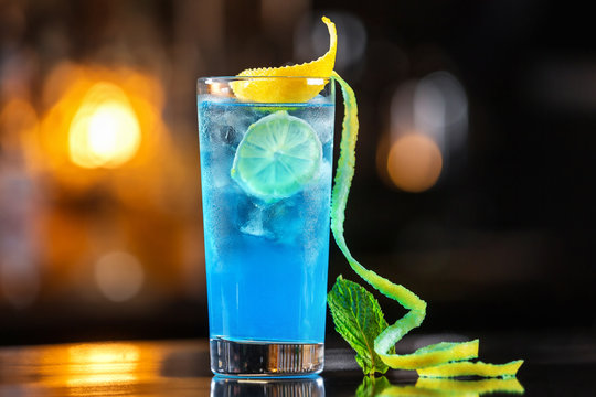 Closeup glass of pacific ocean cocktail decorated with lime at festive bar counter background.