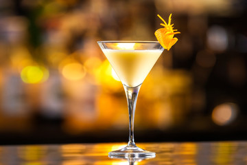 Closeup glass of egg liquor decorated with orange at bright bar counter background.