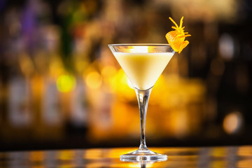 Closeup glass of egg liquor decorated with orange at bright bar counter background.