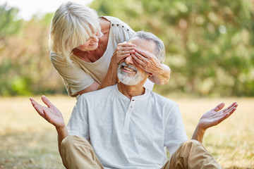 Fototapeta premium Old woman covers her husband's eyes