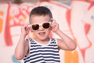 adorable small kid wearing sunglasses on graffiti background