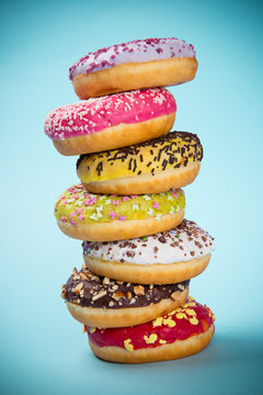Donuts glazed with sprinkles on pastel blue background.