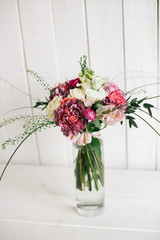 Букет стоит в стеклянной прозрачной вазе на деревянном белом фоне Bouquet is in a glass transparent vase on wooden white background