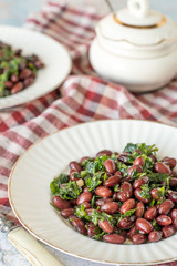 

 Salad of red beans.   Salad of red beans with cilantro and garlic on white plates on a checkered napkin.