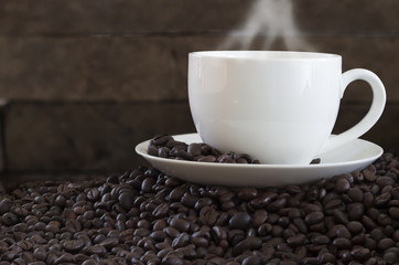 Coffee in a white cup and coffee beans on the floor.