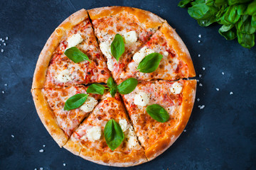 Homemade Pizza with tomato sauce,  olives,  fresh mozzarella, parmesan and basil on the dark background