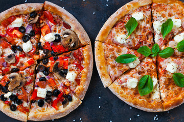 Hot testy pizza with tomatoes, mozzarella, mushrooms, olives, red pepper and basil on black concrete background. Copyspace. Top view.