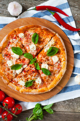 Homemade Pizza with tomato sauce, artichoke hearts, olives, Parmacotto, fresh mozzarella, parmesan and basil on the grey wooden background