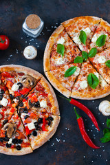 Hot testy pizza with tomatoes, mozzarella, mushrooms, olives, red pepper and basil on black...