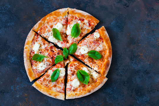 Pizza margarita with tomato sauce, fresh mozzarella, parmesan and basil on the dark  background