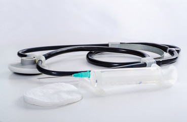disposable syringe and a black stethoscope on a white background