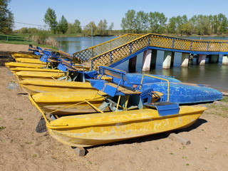 Catamarans and inverted boats on the sandy shore of the lake