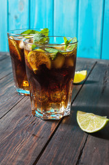 Homemade Cuba Libre with fresh lime, brown rum and crushed ice on an old wooden table