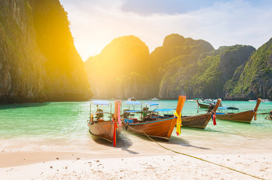 Traditional Long Tail Boat Docking In Maya Bay In Front Of A Clear And Sandy Beach In Krabi Nearby Phuket Island Thailand; Light Filtered