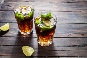 Homemade Cuba Libre with fresh lime, brown rum and crushed ice on an old wooden table
