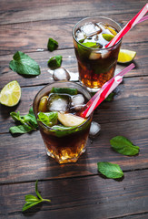 Homemade Cuba Libre with fresh lime, brown rum and crushed ice on an old wooden table