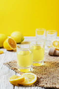Alcoholic drink, Italian liqueur limoncello in wine-glasses with lemons on a wooden background
