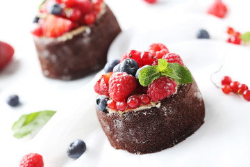 Sweet chocolate cakes with berries on white background