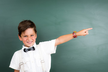 junge zeigt mit finger zur schultafel